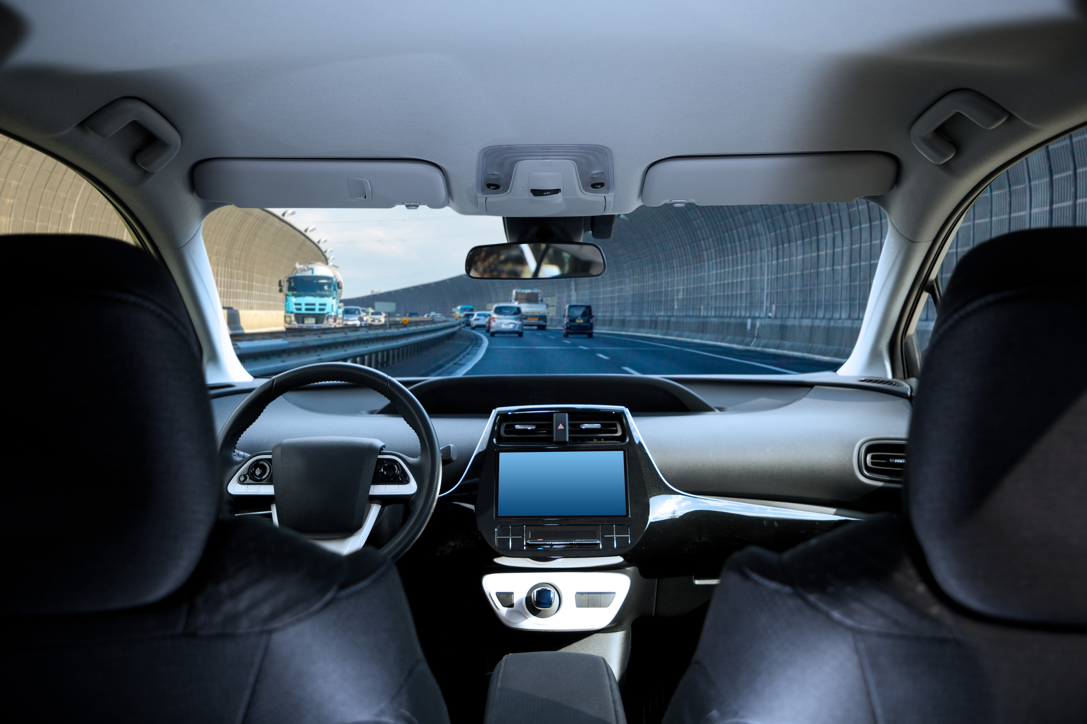 Cockpit of driverless car driving on highway viewed from rear seat.