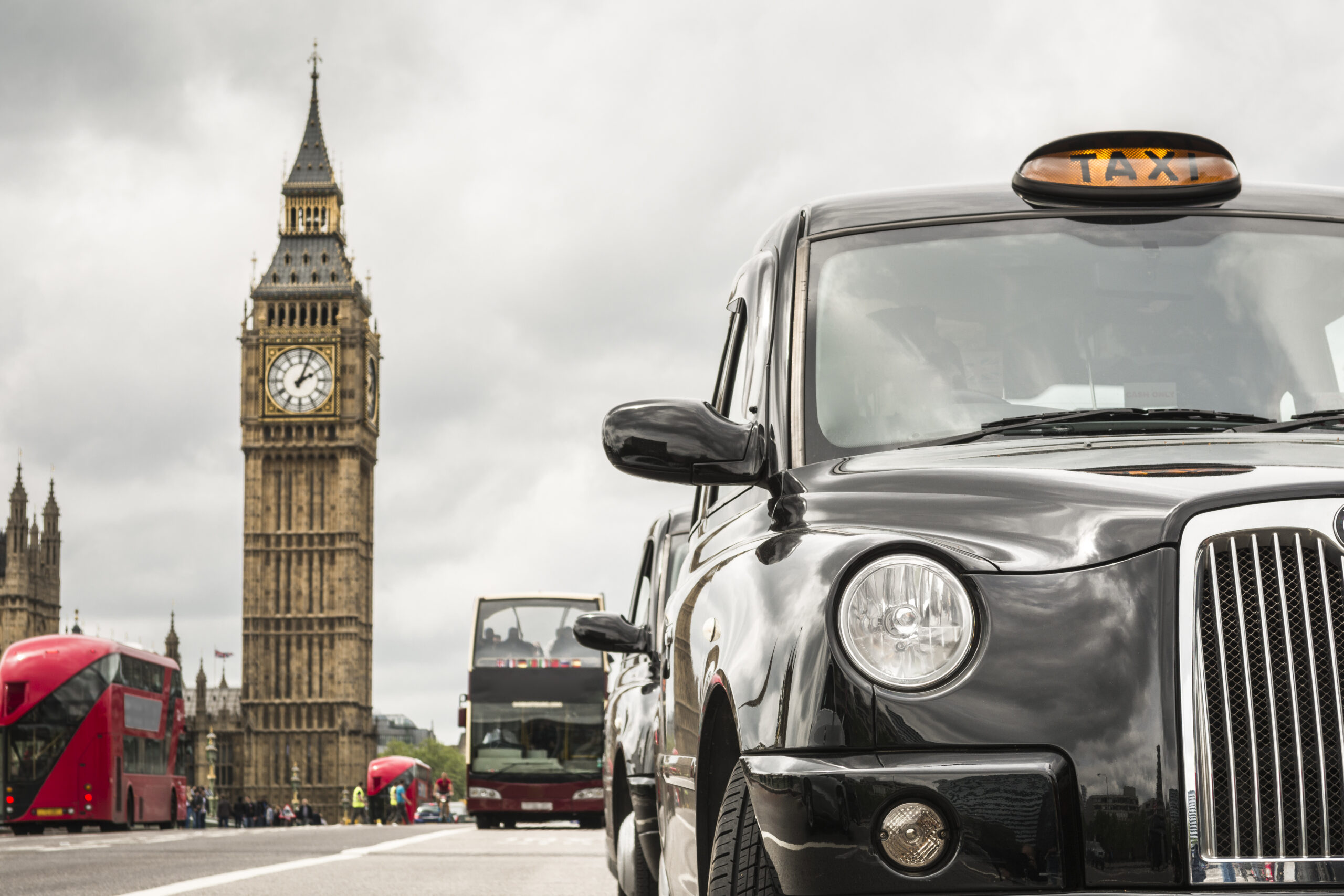 London's taxis and red buses front of big ben on a cloudy day, selective focus
