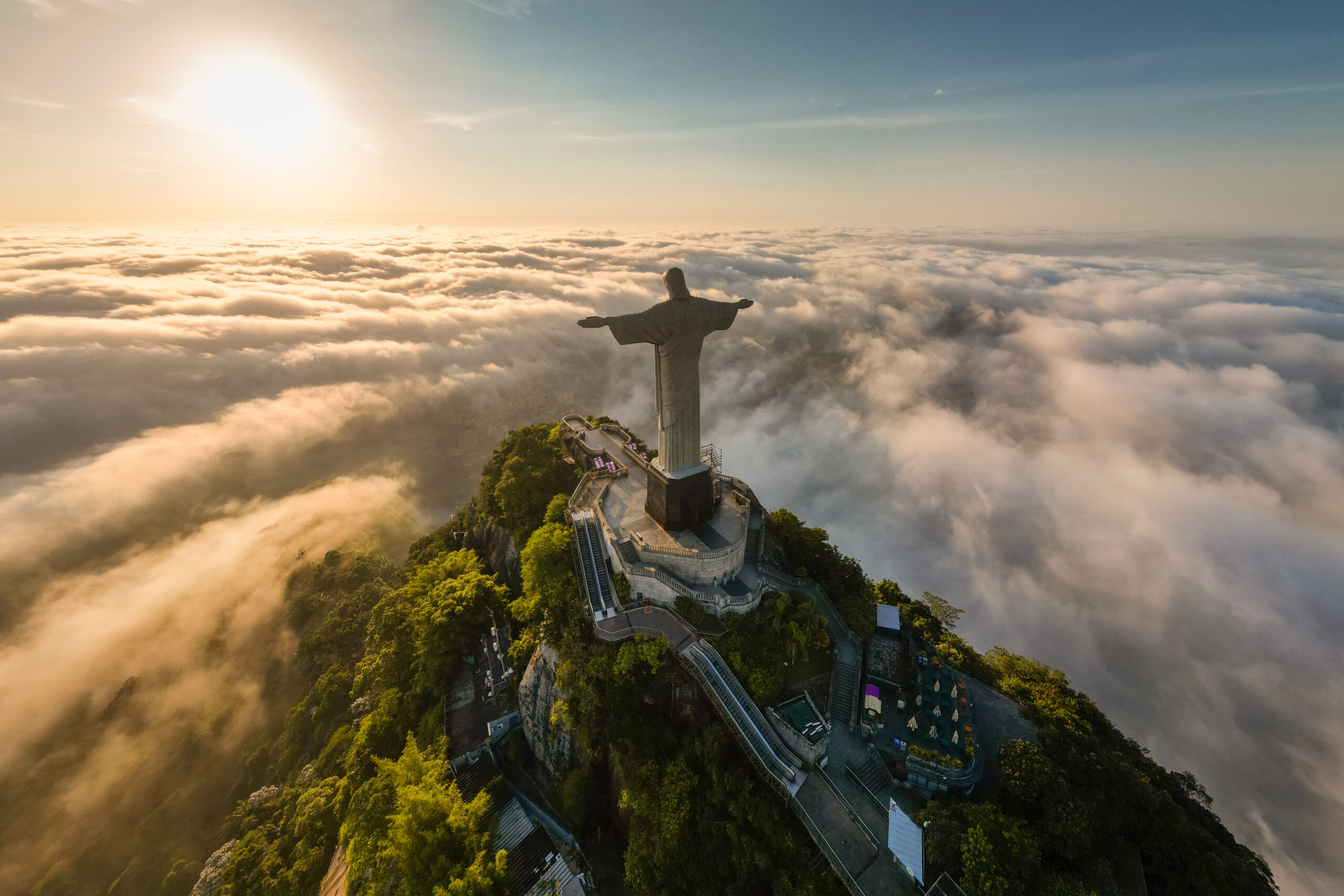 Rio de Janeiro, Brazil - April 11, 2024: Dramatic view of Christ the Redeemer statue on top of the Corcovado mountain above clouds during sunrise.