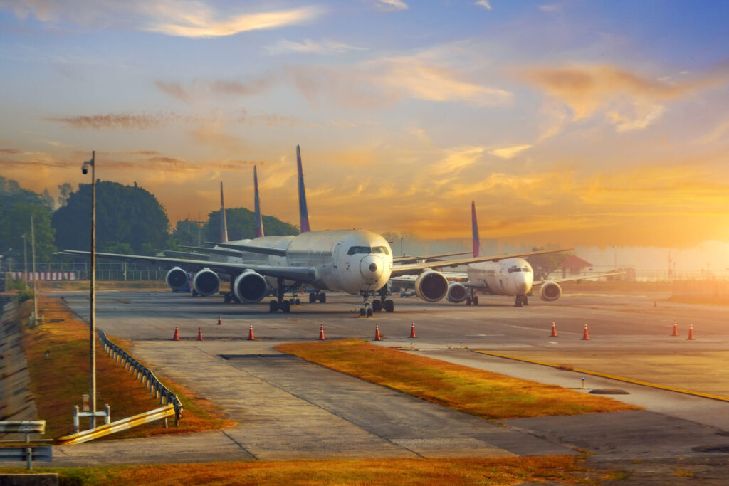 A row of old planes parked in the rays of the morning dawn in the sky.