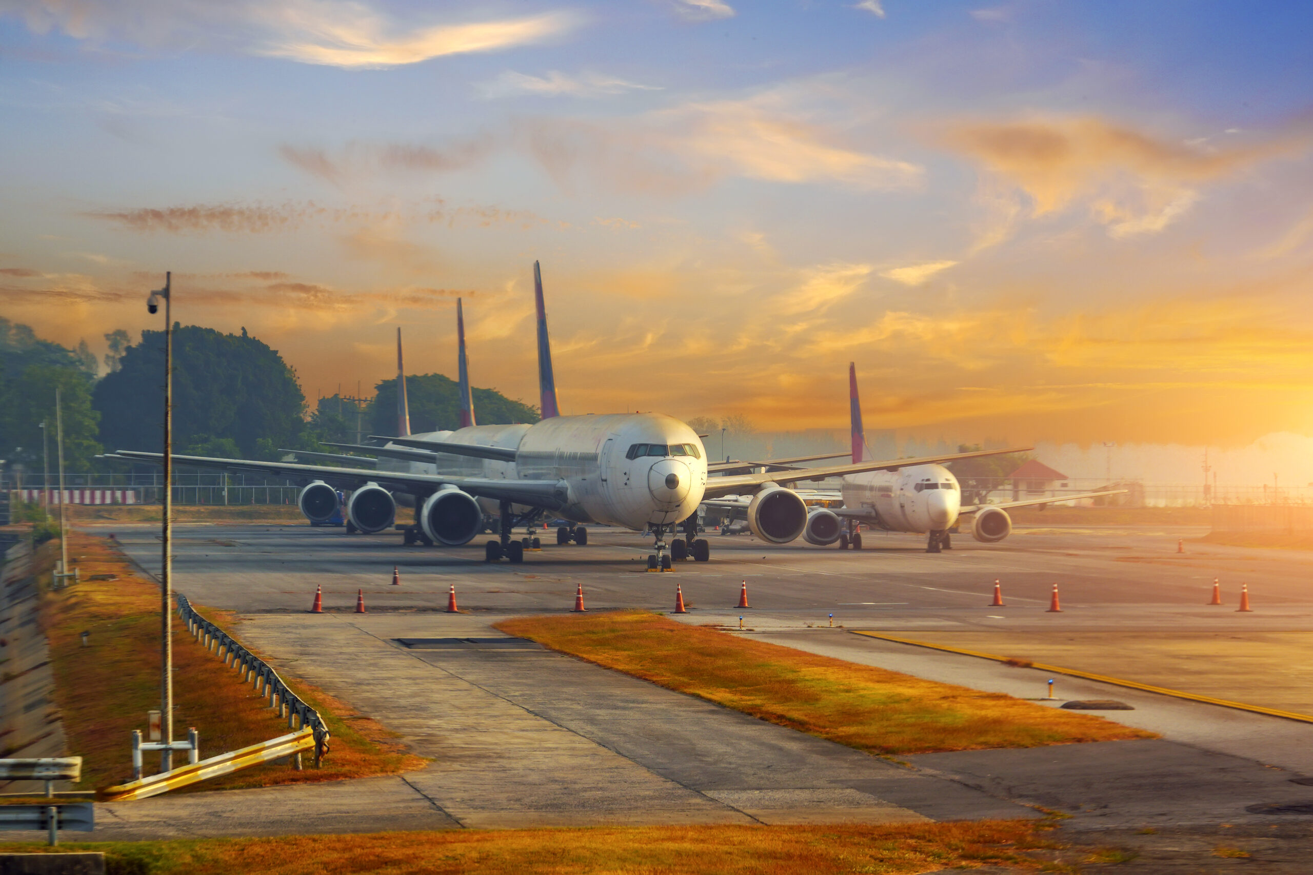 A row of old planes parked in the rays of the morning dawn in the sky.