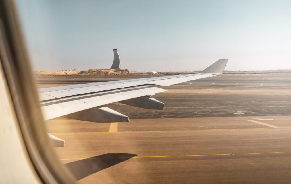 Aerial view out of airplane window while taking off from the runway of the airport during sunset
