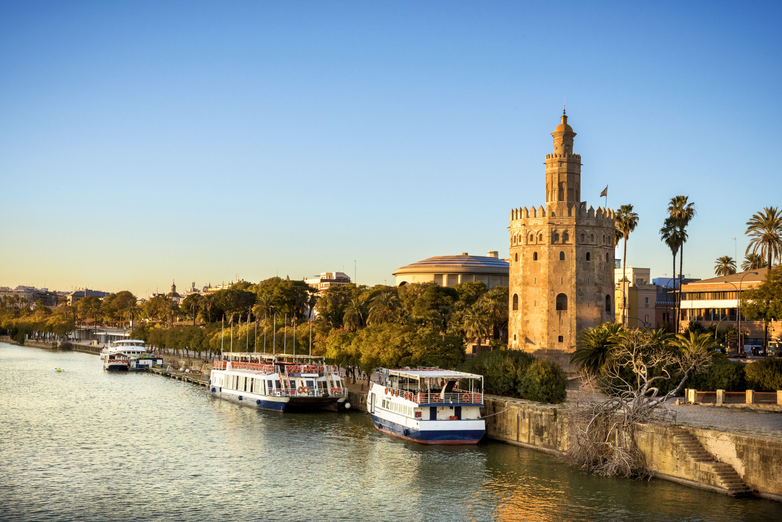 Torre del Oro beside the Guadalquivir river in Seville, with boats along the bank