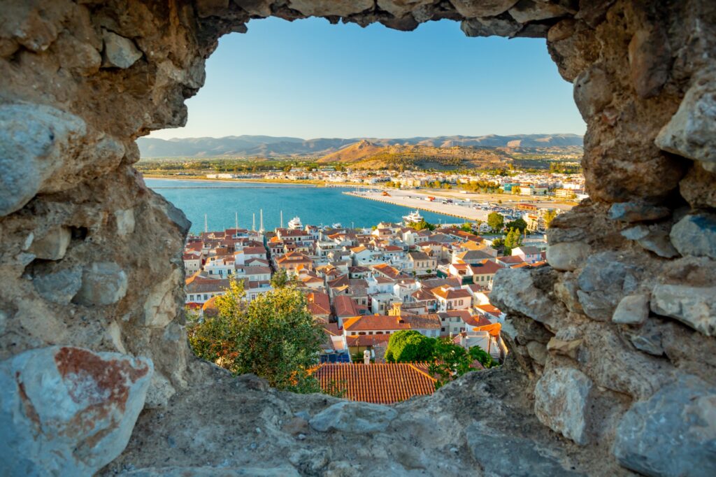 Nafplio rooftops and harbour seen through a stone opening at Palamidi Fortress